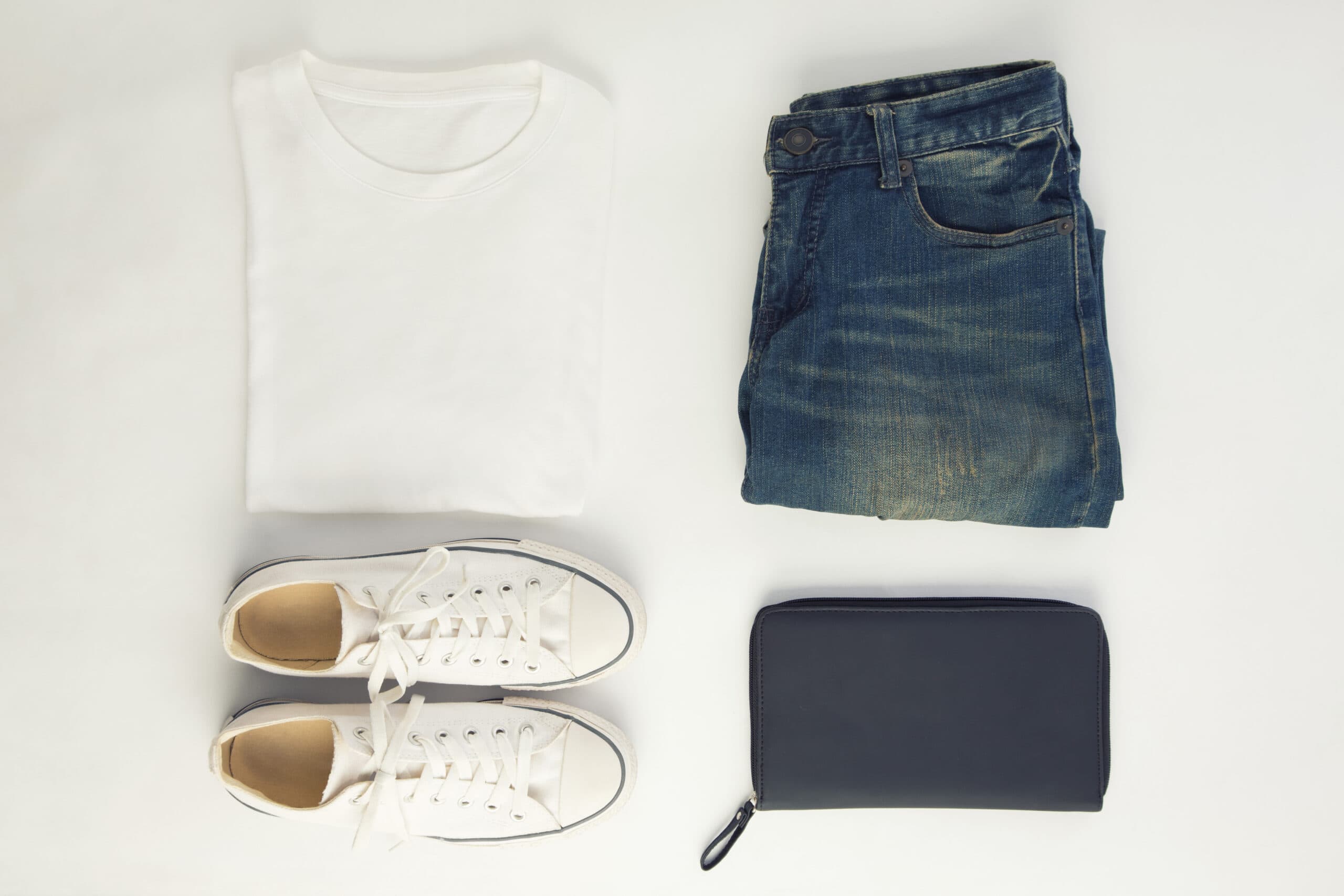 Flat lay of a white t-shirt, jeans, sneakers and a wallet